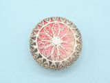 a close up of a pink and silver broochle on a blue surface