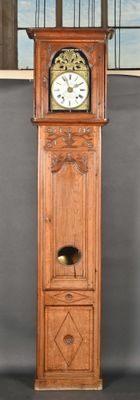 une grande horloge de parquet en bois placée devant une fenêtre