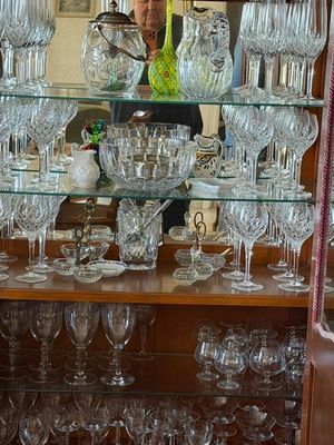 un homme debout derrière une vitrine remplie de verres à vin