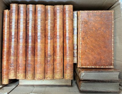several old books are stacked in a cardboard box on a table