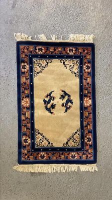 un tapis accroché au mur, sur lequel figure l'image de deux oiseaux
