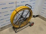 a yellow hose on a cart in front of a wall