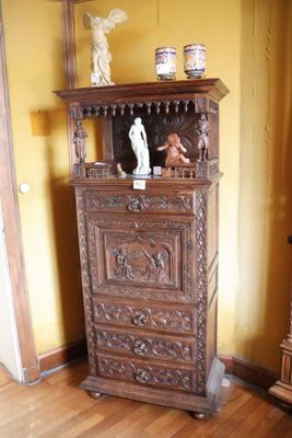 une armoire en bois surmontée d'une statue, dans une pièce