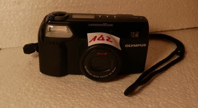 un appareil photo noir, sur lequel est collé un autocollant, posé par terre