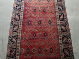 a red rug with a blue border on a white floor