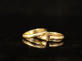 a pair of gold wedding rings on a black surface