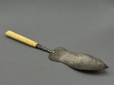une cuillère en argent avec un manche en bois posée sur une surface grise