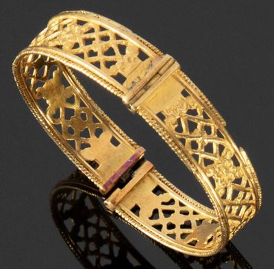 gros plan d'un bracelet en or sur une surface noire