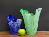 two glass vases sitting on a table next to a green apple