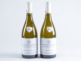 two bottles of white wine sitting next to each other on a white surface