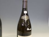 a bottle of wine sitting on a counter next to a glass of wine