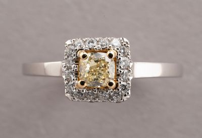 a close up of a ring with a yellow diamond surrounded by white diamonds