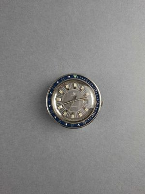 a close up of a watch on a table with a gray background