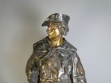 une statue en bronze représentant un homme portant un chapeau et un manteau