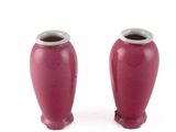 deux vases rouges posés l'un à côté de l'autre sur une surface blanche