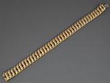 gros plan d'un bracelet en chaîne en or sur une surface grise
