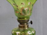 a green glass lamp that is on a gold stand