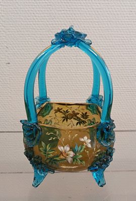 a small blue basket with flowers on it on a table
