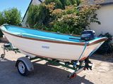 un petit bateau sur une remorque garé devant une maison