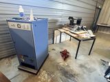 a blue refrigerator sitting in a garage next to a table with a bottle of water on it