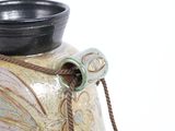a vase with a rope around it and a bowl on top of it