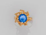 gros plan d'une bague en or avec une pierre bleue au centre