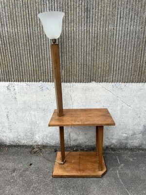 une table en bois sur laquelle est posée une lampe, à côté d'un mur en béton