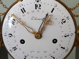 a clock that is hanging on a pole with chains