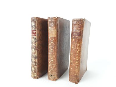 three old books are stacked on top of each other on a white surface