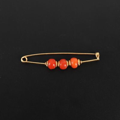 une broche ornée de perles d'or et de corail
