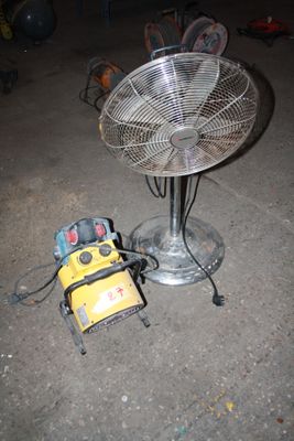 un ventilateur posé par terre à côté d'une table