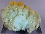 a small piece of green and yellow mineral on a clear base