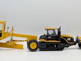 two toy tractors and a bulldozer on a white surface