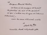 un livre ouvert, sur lequel est inscrit un poème écrit à la main, posé sur une table