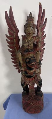 statue en bois représentant un homme tenant un oiseau sur une table bleue
