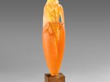 an orange jade carving of a woman on a wooden base
