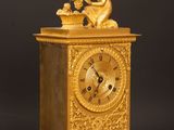 a gold clock sitting on a wooden table with a black background