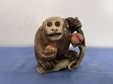 une figurine représentant un singe assis sur une branche d'arbre