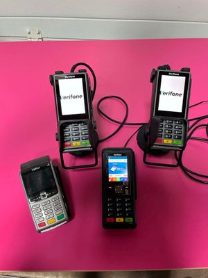 trois téléphones portables sont branchés sur un chargeur posé sur une surface rose