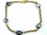 un gros plan sur un bracelet à chaîne en or orné de perles noires