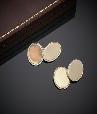 deux boutons de manchette en argent et en or et un livre posés sur une table