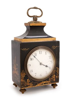 une horloge noire et or posée sur une surface blanche