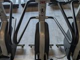 a row of tread machines in a gym with a clock on the wall