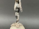 an antique silver figurine of a woman on a ball