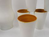 four white vases sitting next to each other on a table