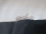 a white pillow on a bed with a black blanket