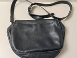 the small black purse is sitting on a white table