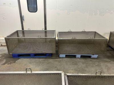 deux grands bacs métalliques posés sur des palettes dans un entrepôt