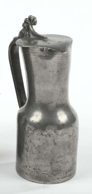 a silver pitcher sitting on a table next to a vase