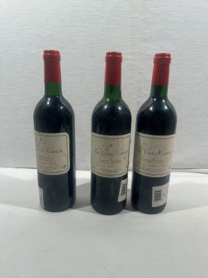 trois bouteilles de vin rouge sont posées les unes à côté des autres sur une surface blanche